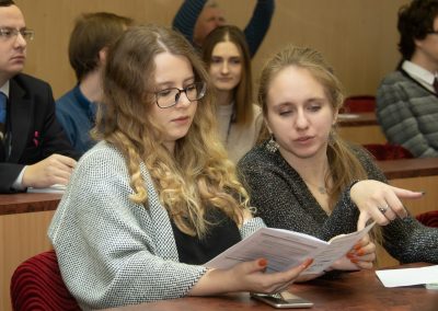 Two young women at a youth forum, reading and discussing a paper.