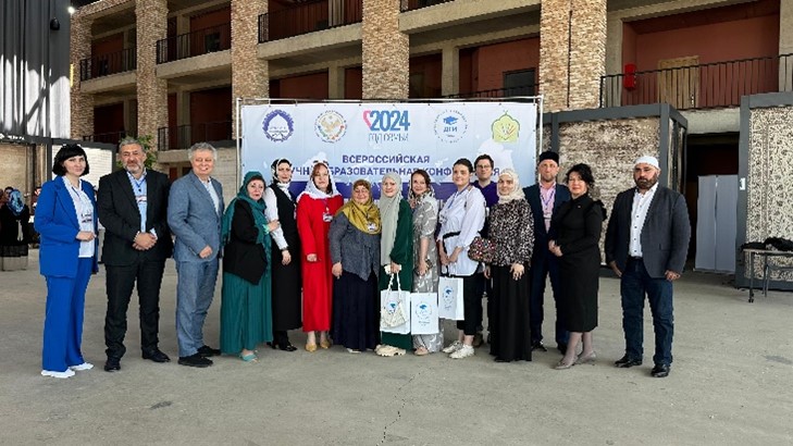 A group of conference delegates posing together in front of a banner for the Religion and Family Values Conference held in Mahachkala in 2024.