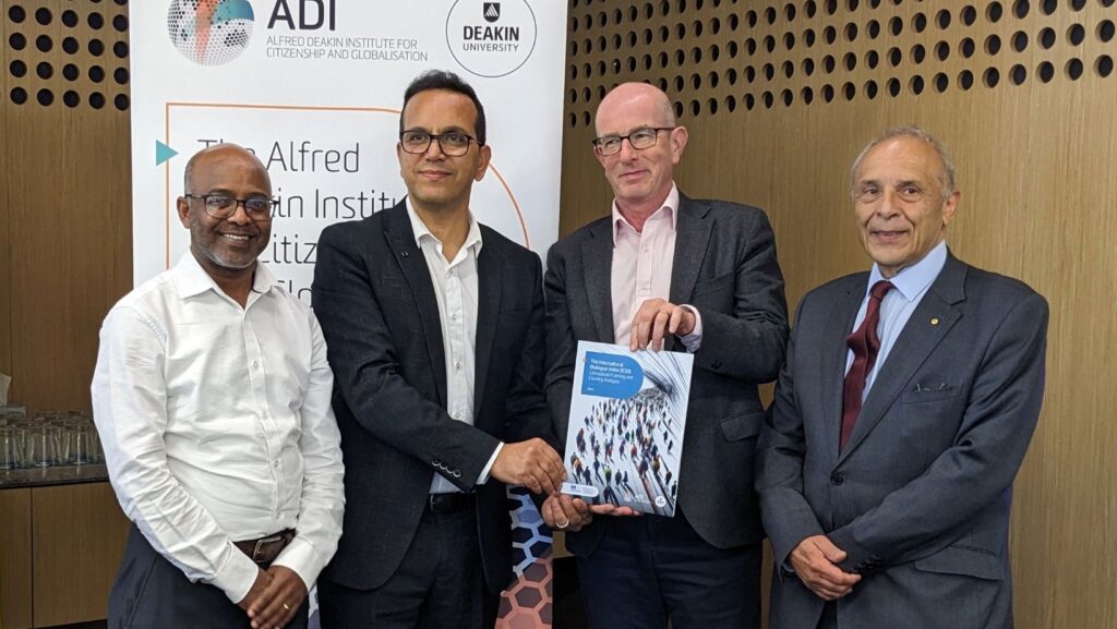 Four professionally dressed men standing together around a report.